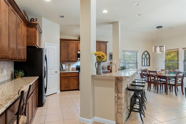 kitchen featuring tasteful backsplash, light stone countertops, and a kitchen breakfast bar