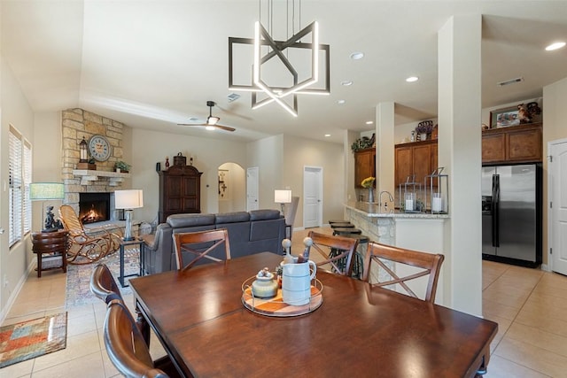 dining space with ceiling fan, a fireplace, light tile patterned floors, and sink