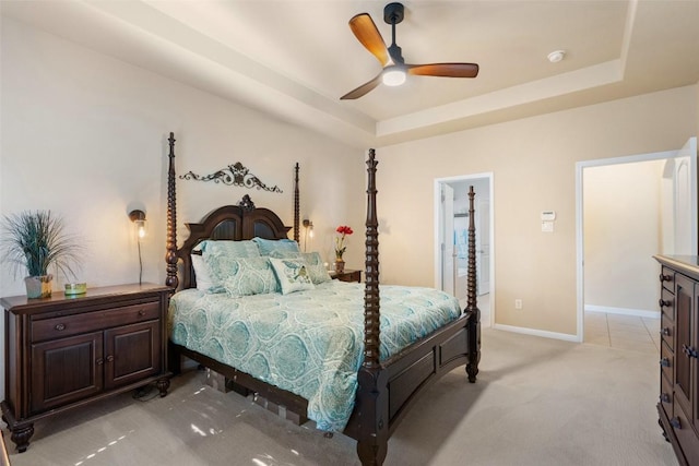 carpeted bedroom featuring ceiling fan and a tray ceiling