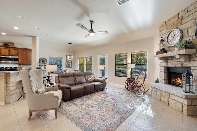 tiled living room featuring ceiling fan and a fireplace