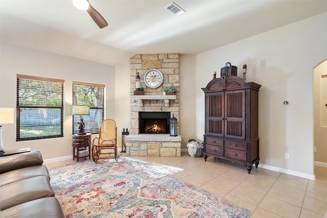 tiled living room featuring a fireplace and ceiling fan