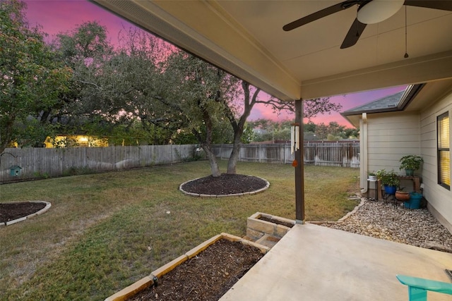 yard at dusk with ceiling fan and a patio area