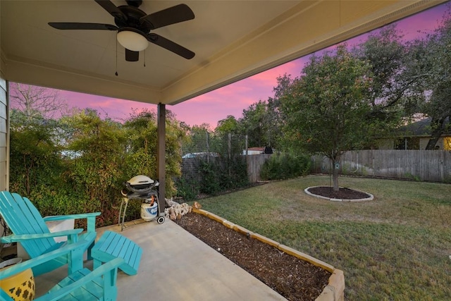 patio terrace at dusk with ceiling fan and a yard