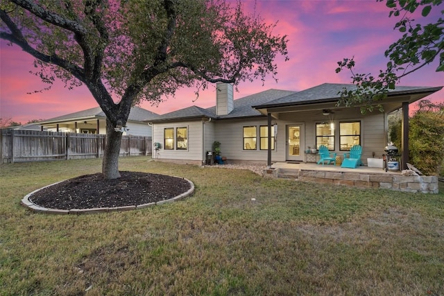 back house at dusk featuring a yard and ceiling fan