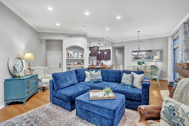 living room with light wood-type flooring, crown molding, and an inviting chandelier