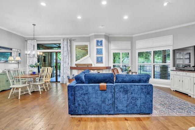 living room featuring a chandelier, ornamental molding, and light wood-type flooring