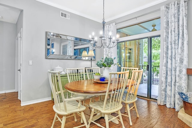 dining area with a notable chandelier, wood-type flooring, and ornamental molding