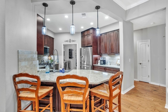 kitchen featuring kitchen peninsula, appliances with stainless steel finishes, backsplash, light wood-type flooring, and sink