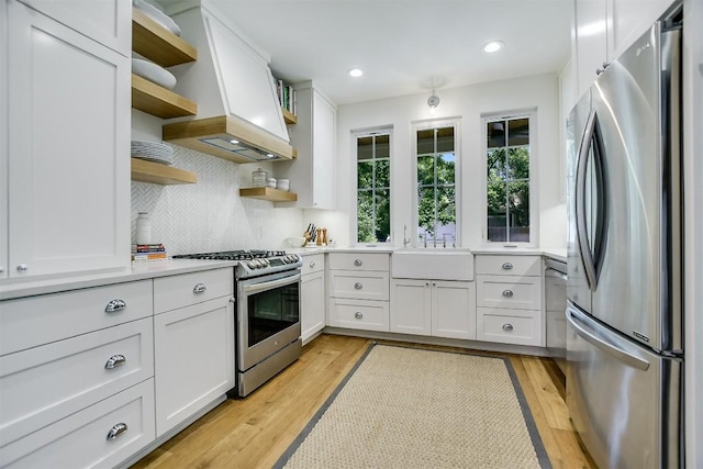 kitchen with white cabinets, light wood-type flooring, sink, and appliances with stainless steel finishes