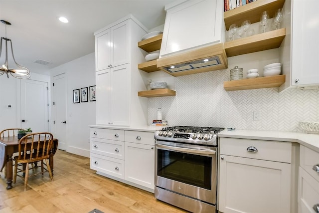 kitchen with pendant lighting, light wood-type flooring, custom range hood, gas stove, and white cabinetry