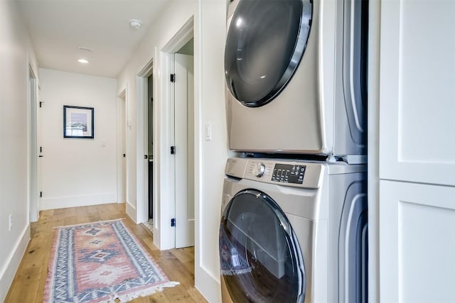 washroom featuring stacked washer and dryer and light hardwood / wood-style flooring