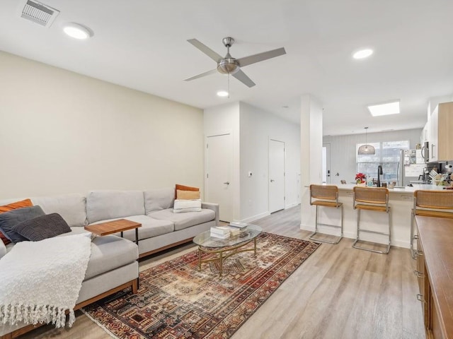 living room with light hardwood / wood-style flooring and ceiling fan