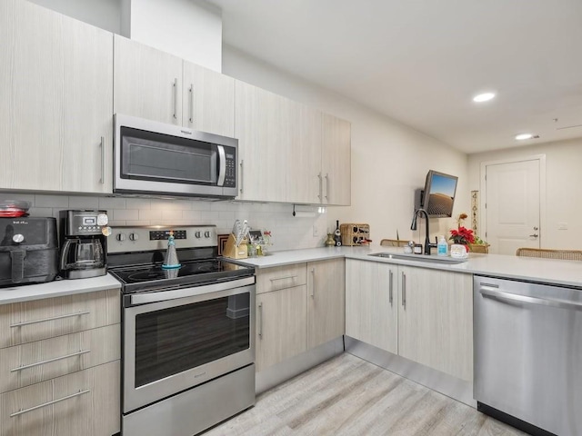 kitchen featuring sink, light hardwood / wood-style flooring, decorative backsplash, light brown cabinetry, and stainless steel appliances