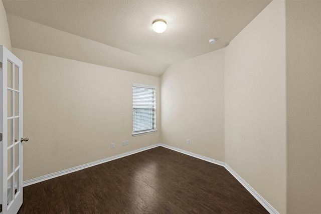 empty room featuring a textured ceiling, vaulted ceiling, and hardwood / wood-style flooring