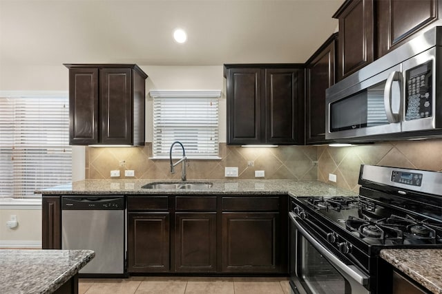 kitchen featuring appliances with stainless steel finishes, light stone counters, plenty of natural light, and sink