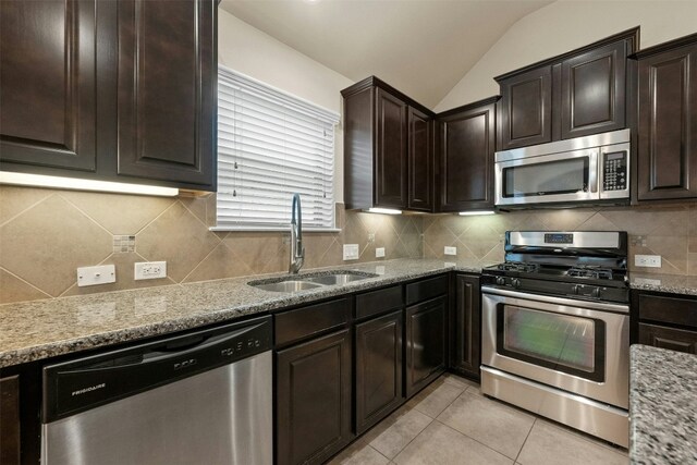 kitchen with light stone countertops, appliances with stainless steel finishes, light tile patterned floors, and sink