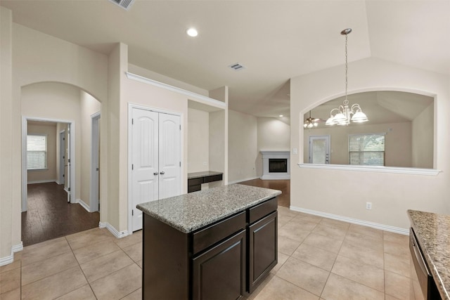 kitchen with light wood-type flooring, light stone counters, vaulted ceiling, decorative light fixtures, and a chandelier