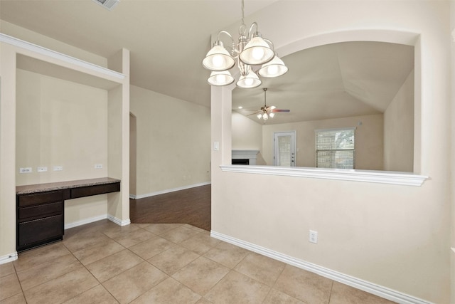 interior space with vaulted ceiling, ceiling fan with notable chandelier, and light tile patterned floors