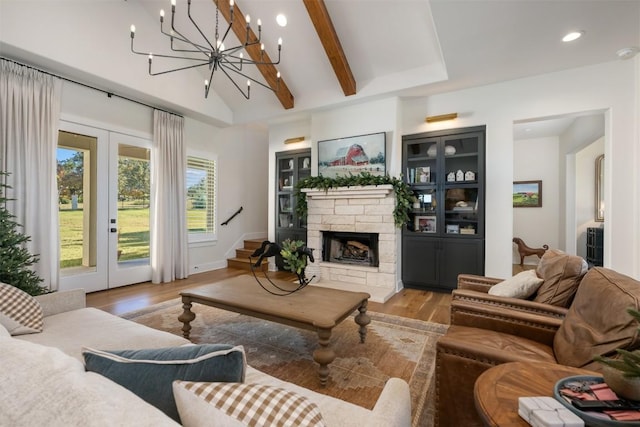 living room featuring french doors, an inviting chandelier, vaulted ceiling with beams, a fireplace, and light hardwood / wood-style floors