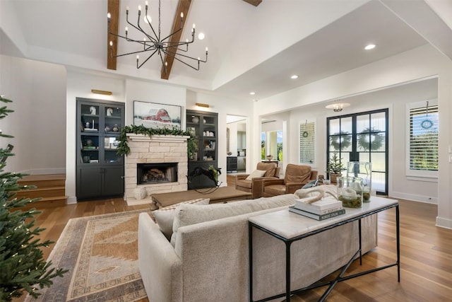 living room featuring a notable chandelier, a stone fireplace, wood-type flooring, and high vaulted ceiling