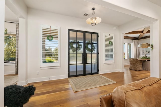 doorway with beamed ceiling, wood-type flooring, and french doors