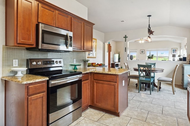 kitchen featuring ceiling fan, kitchen peninsula, pendant lighting, vaulted ceiling, and appliances with stainless steel finishes