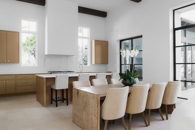 tiled dining space featuring beam ceiling and a towering ceiling