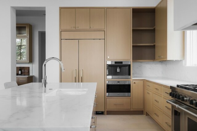 kitchen with light brown cabinetry, stainless steel appliances, light stone counters, and a wealth of natural light