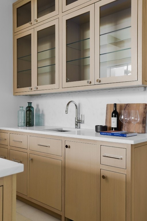 bar featuring backsplash, light brown cabinetry, and sink