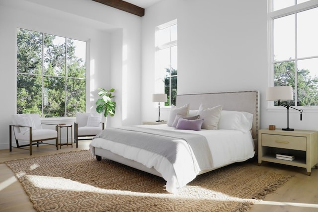 bedroom with wood-type flooring, multiple windows, and beam ceiling