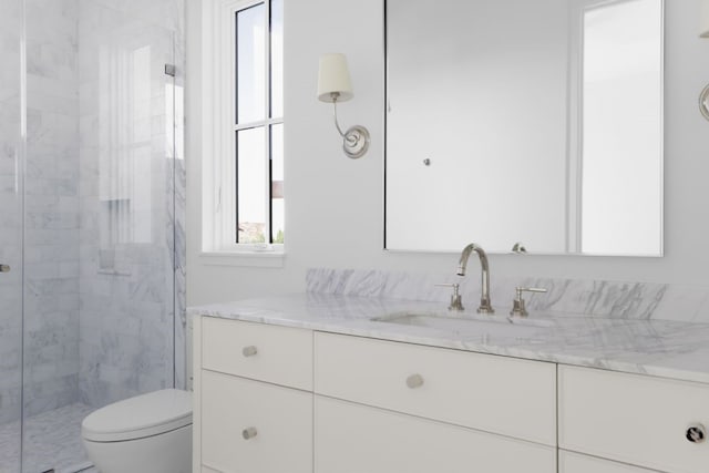 bathroom featuring a shower with door, vanity, and toilet