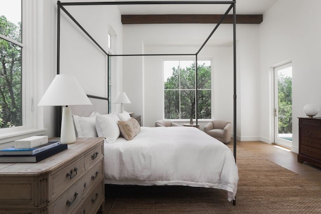 bedroom featuring access to outside, wood finished floors, and beamed ceiling