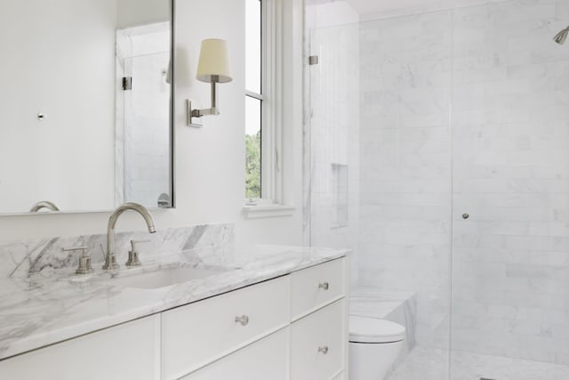 full bathroom featuring vanity, a tile shower, and toilet