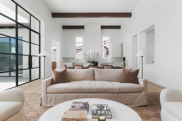 living room featuring wood finished floors, beam ceiling, and baseboards