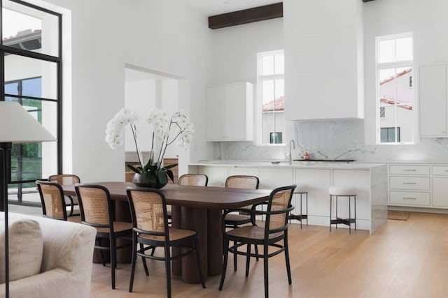 dining room featuring a healthy amount of sunlight, light wood-style floors, and beamed ceiling