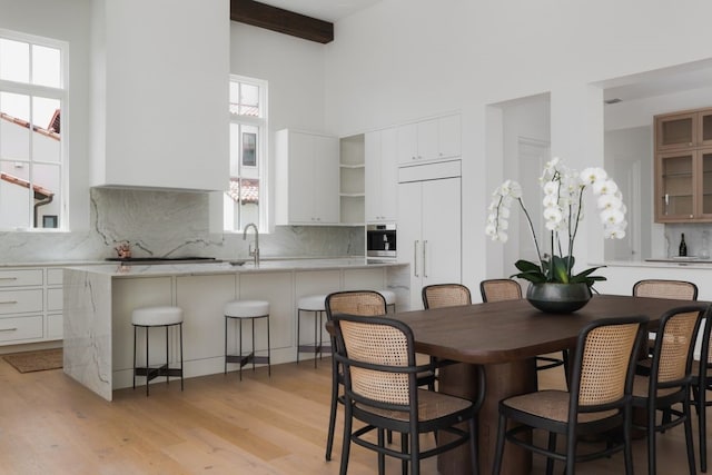 dining space with beamed ceiling and light wood-style floors