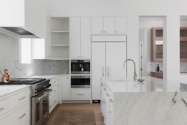 kitchen featuring high end appliances, premium range hood, light stone counters, and open shelves