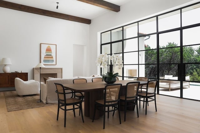 dining space with beam ceiling and light wood finished floors