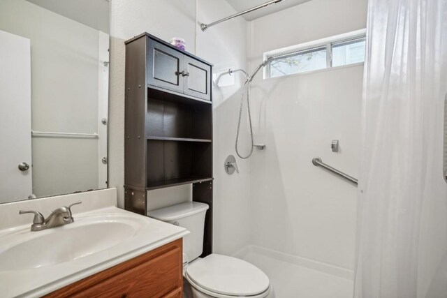 bathroom featuring vanity, toilet, and walk in shower