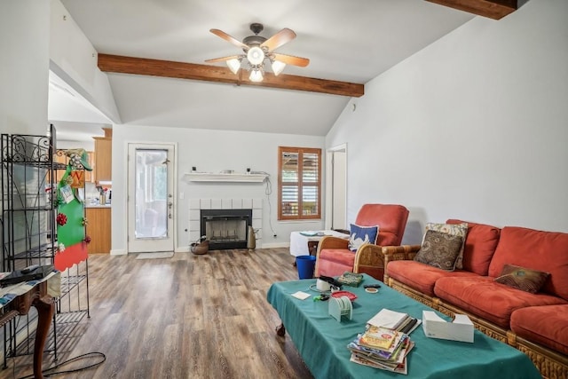 living room with a tile fireplace, wood-type flooring, vaulted ceiling with beams, and ceiling fan