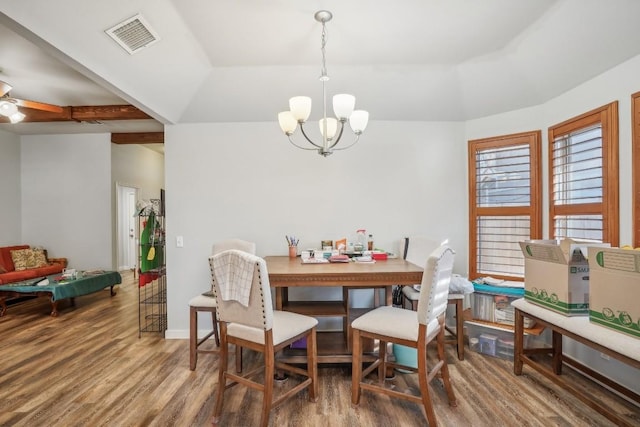 dining space featuring an inviting chandelier, a raised ceiling, hardwood / wood-style floors, and lofted ceiling with beams