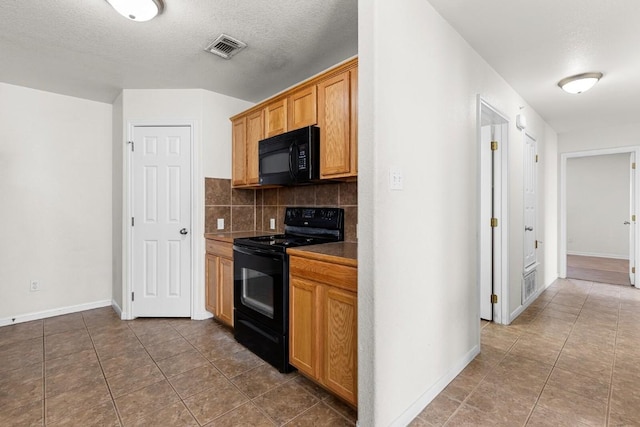 kitchen with black appliances, decorative backsplash, tile patterned floors, and a textured ceiling