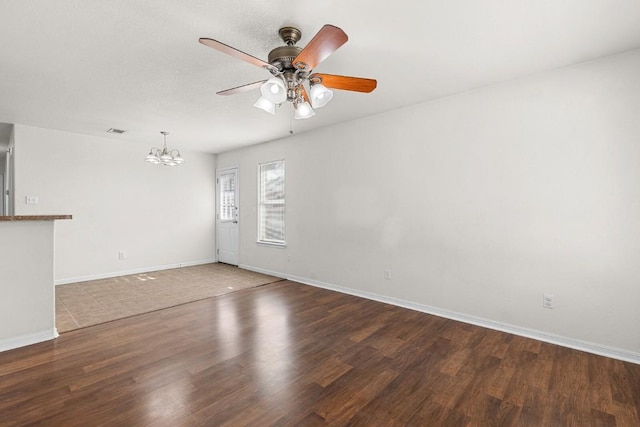 unfurnished room with dark hardwood / wood-style floors and ceiling fan with notable chandelier