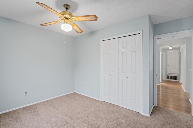 unfurnished bedroom with ceiling fan, light colored carpet, a textured ceiling, and a closet