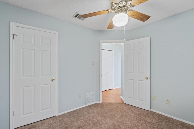 unfurnished bedroom with ceiling fan, light colored carpet, and a textured ceiling