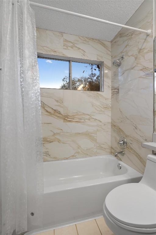 bathroom with tile patterned floors, toilet, a textured ceiling, and shower / tub combo