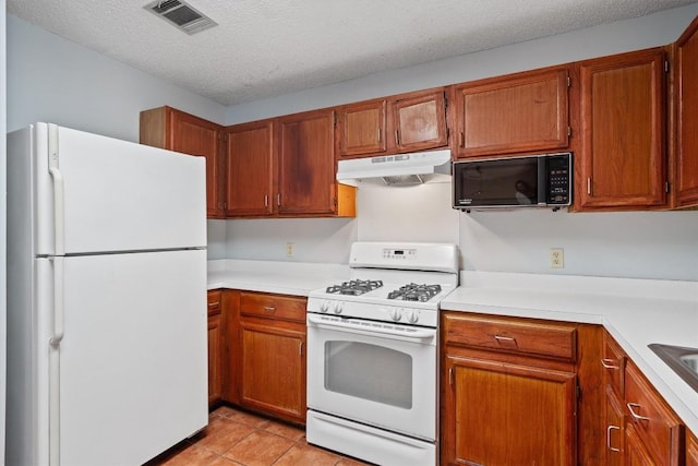 kitchen featuring white appliances, a textured ceiling, and light tile patterned floors