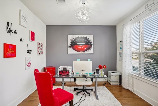 office with hardwood / wood-style flooring and an inviting chandelier