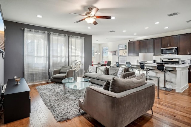 living room with ceiling fan and light wood-type flooring