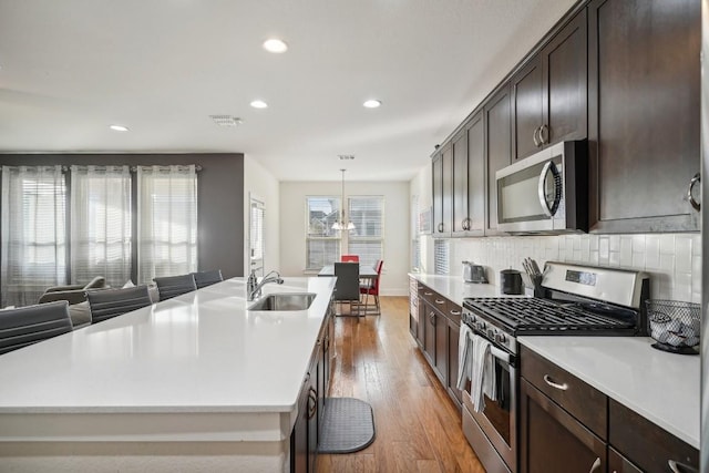 kitchen featuring light hardwood / wood-style floors, a kitchen island with sink, sink, and appliances with stainless steel finishes